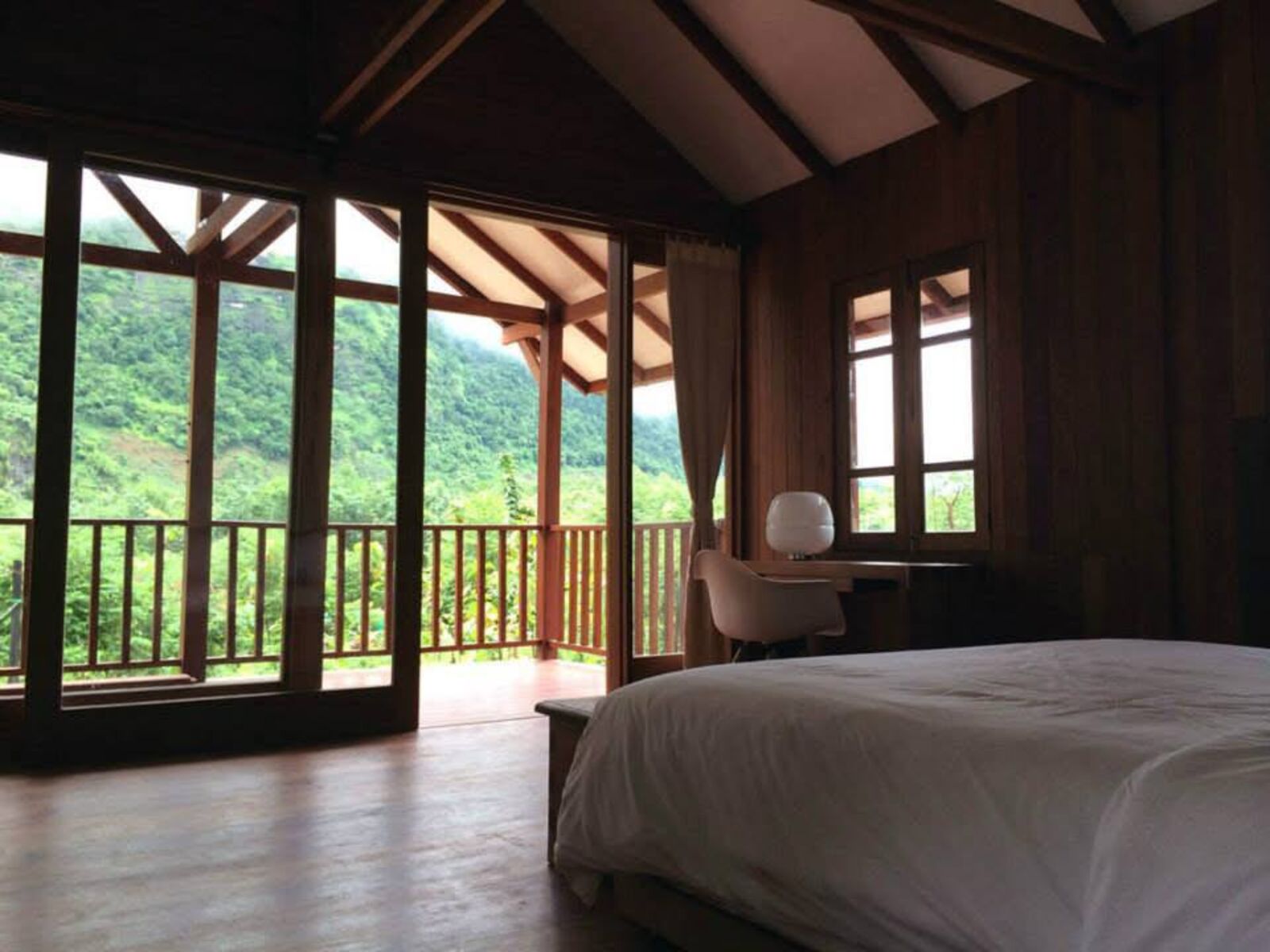 Guest room opening onto a balcony with a view of the forested mountain