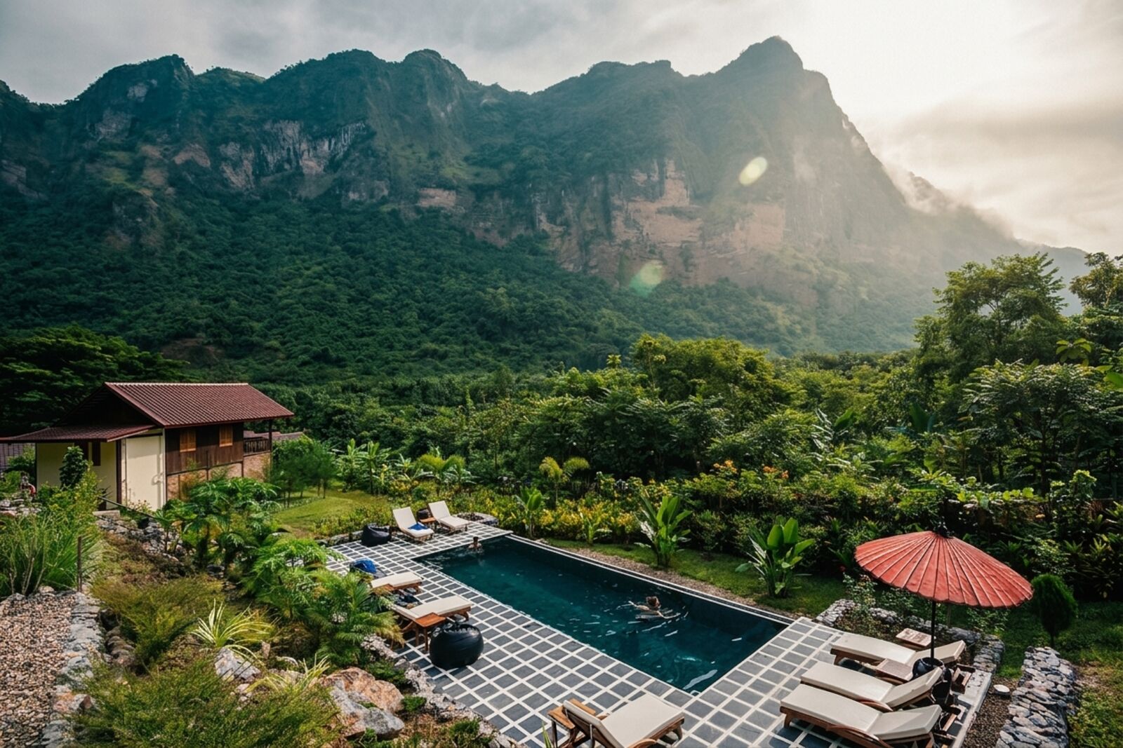 Swimming pool at Keinnara Hpa-An, with loungers, a red umbrella, and Mount Zwekabin behind the lodge